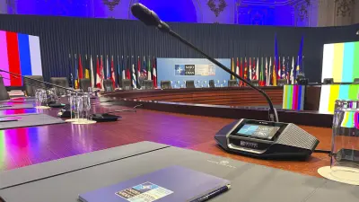 View of the empty NATO conference room with a DICENTIS Discussion device with touchscreen in focus.