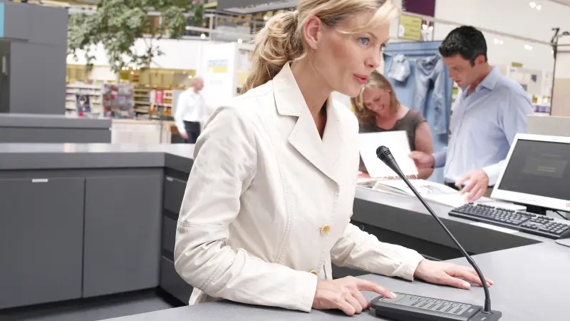 Female employee speaking into a call station from behind a counter in a store