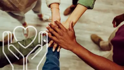 Diverse group of hands stacked together in teamwork, symbolizing social responsibility, inclusion, collaboration, and community support.